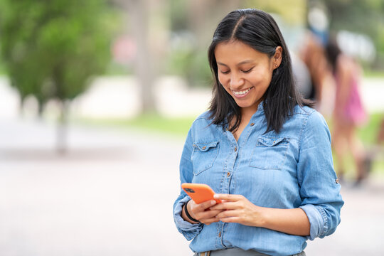Smiling woman browsing smartphone in park