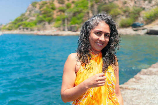 Contemplative ethnic traveler in pareo on pier against sea