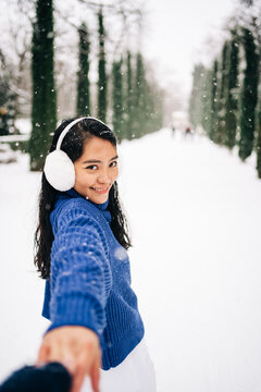 Smiling Asian woman with crop partner on snowy pathway