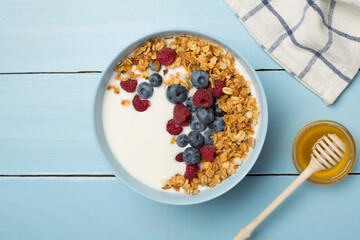 Bowl with granola, yogurt and fresh berries on wooden background, top view
