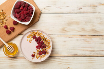 Bowl with granola, yogurt and fresh berries on wooden background, top view