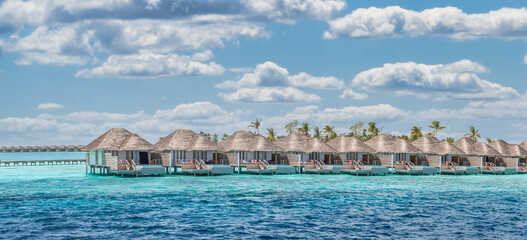 Aerial view of Maldives island, luxury water villas resort and wooden pier. Beautiful sky and ocean...