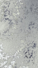 Winter mobile phone wallpaper. Vertical Christmas backdrop. Pale yellow and gray tinted background. Drawing of ice crystals and frost on the window glass in winter. Crystal pattern. Macro