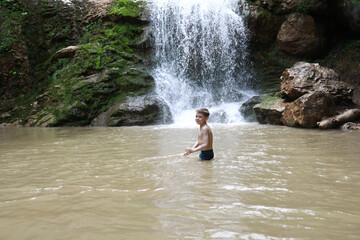 Boy bathing in Rufabgo stream next to waterfall Shum