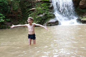 Boy posing in Rufabgo stream next to waterfall Shum