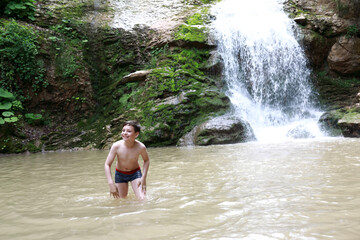 Fototapeta na wymiar Happy boy bathing in Rufabgo stream next to waterfall Shum