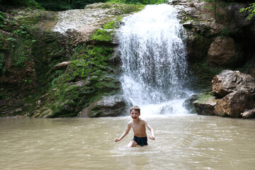 Kid bathing in Rufabgo stream next to waterfall Shum