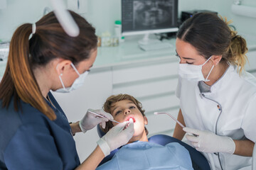 Female dentists curing teeth of boy