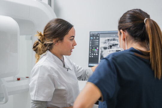 Female dentists examining teeth X ray on computer