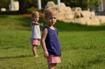Twin girls. Sisters two years old. Cute positive kids play in the park. The sisters look alike. Family bonds