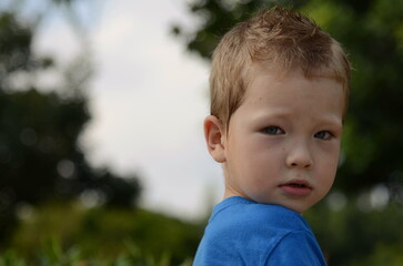 Portrait of a little boy. Emotions of the child, smile, sadness, thoughtful look. Blond boy with blue eyes, close-up, space for text