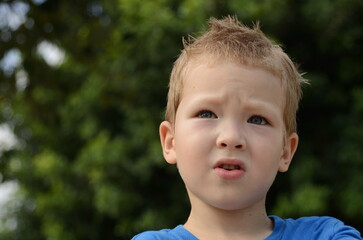 Portrait of a little boy. Emotions of the child, smile, sadness, thoughtful look. Blond boy with blue eyes, close-up, space for text