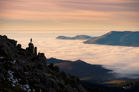 Man standing on high rock and looking at sunset
