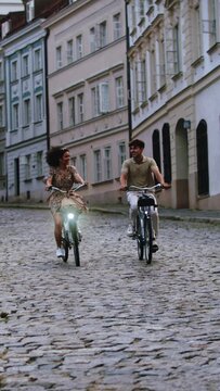 Stylish young couple riding bikes on an old European cobbled bricked road