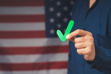 Hand holding a green check mark symbol while standing on the American flag background