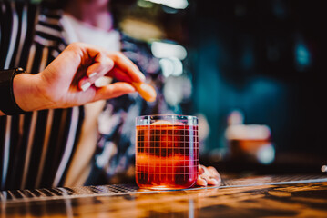 woman hand bartender making negroni cocktail in bar