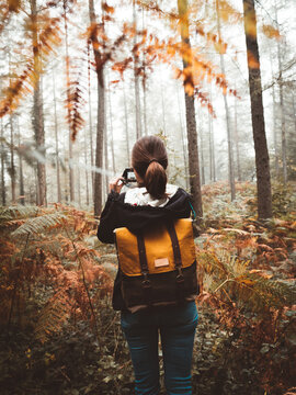 Woman exploring a foggy forest and taking photos with compact camera