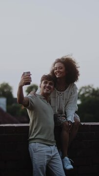 couple taking a selfie sitting on brick wall
