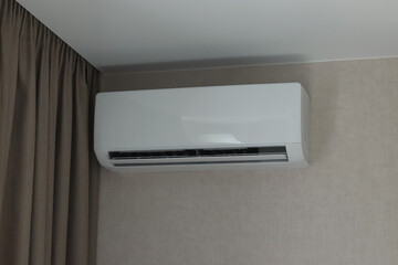 working air conditioner on gray wall near curtain