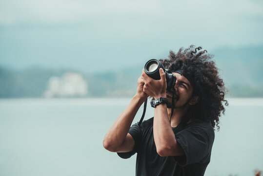 Black photographer taking photo of sea on professional camera