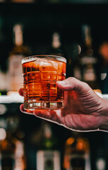 man hand holding a glass of whiskey in a bar