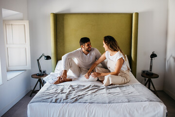 Calm young couple sitting on comfortable bed in apartment