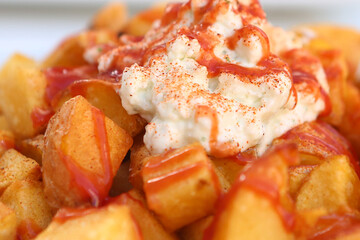baked potato with garlic sauce aioli and tomato ketchup on square plate with human hands closeup photo
