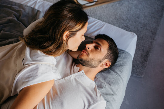 Calm young couple cuddling on comfortable bed in apartment