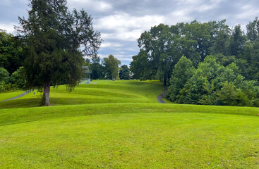 Walking path at prehistoric Great Serpent Mound Earthworks snake effigy in Ohio USA. Body of snake curves along the landscape in largest effigy mound in the world. Dramatic sky woodland background.