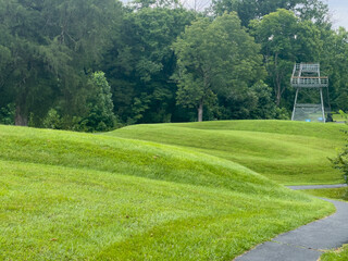 Walking path at prehistoric Great Serpent Mound Earthworks snake effigy in Ohio USA. Body of snake curves along the landscape in the largest effigy mound in the world. Observation tower in background.