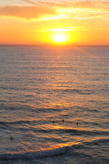 surfers in the sea at sunset from the cliffs of fortaleza de sagres