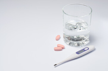 Medical electronic thermometer and tablets on a white background. The concept of diagnosis and treatment of diseases.