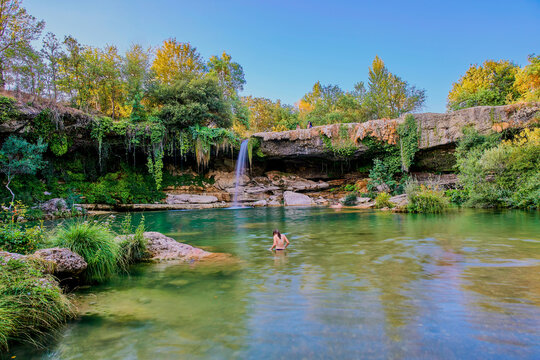 Girl enjoying a sunny day at the Cascada de Pedrosa de Tobalina, Burgos, Spain. Long exposure photo.
