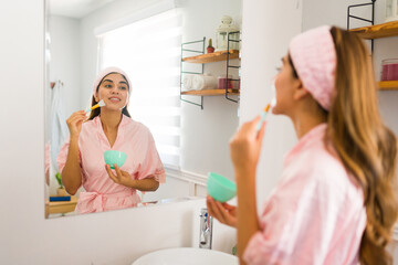 Attractive woman in a bathrobe using a facial mask in the morning