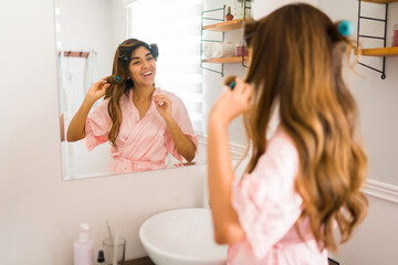 Cheerful woman smiling while doing a curly hairstyle in the bathroom