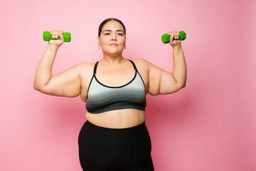 Determined fat woman lifting weights and losing weight with exercise