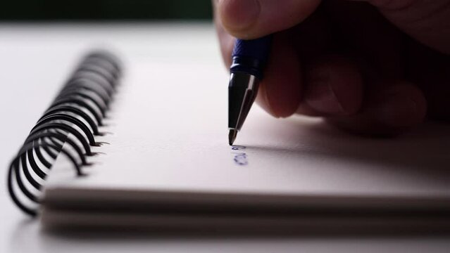 Concept of writing paper, letter, pen, notepad, diary. close-up man hand writing paper notebook with blue pen to note, memo, list action plan at office or home desk, selective focus 4k resolution