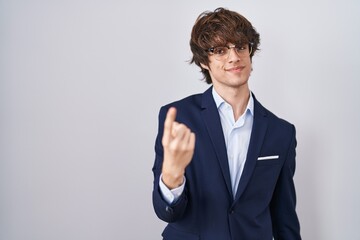 Hispanic business young man wearing glasses beckoning come here gesture with hand inviting welcoming happy and smiling