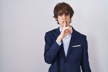 Hispanic business young man wearing glasses asking to be quiet with finger on lips. silence and secret concept.