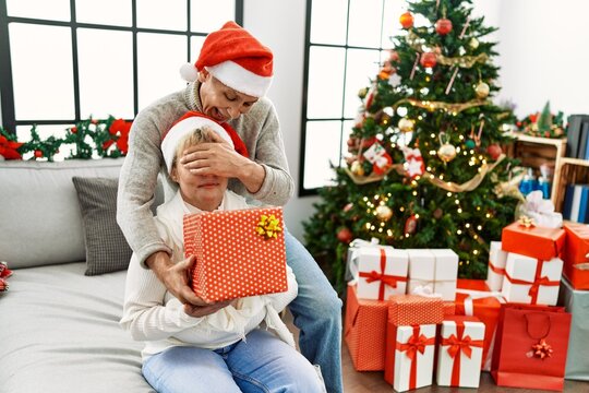 Senior man suprising his wife with christmas gift at home.