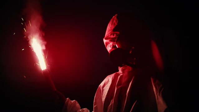 Scientist picking biohazardous samples in the infected area. Wearing hazmat suits, holding signal flare with red flame. Night work in dangerous zone