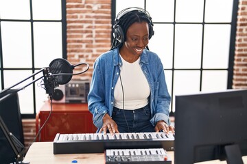 African american woman musician playing piano keyboard at music studio