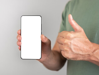 Man holding phone mockup with thumb up gesture. Male recommending, approving smartphone application