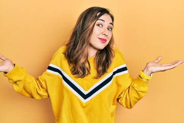 Young hispanic girl wearing casual clothes clueless and confused expression with arms and hands raised. doubt concept.