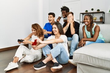 Group of young friends smiling happy playing video game at home.