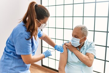 Senior man with safety mas getting vaccinated with covid 19 immunity vaccine, nurse injecting...