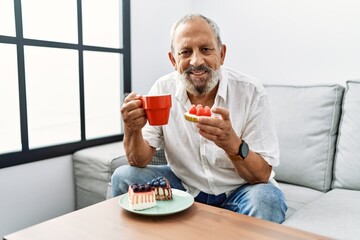 Senior grey-haired man smiling confident having breakfast at home