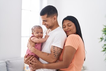 Hispanic family hugging each other standing at home