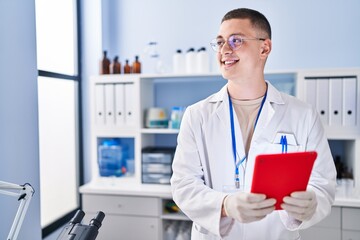 Young hispanic man scientist smiling confident using touchpad at laboratory