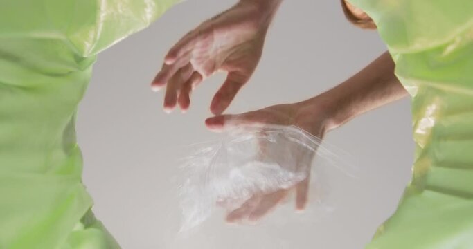 Person hands compress plastic tray and throw into green trash bin. Adult takes care of apartment throwing garbage in can close bottom view